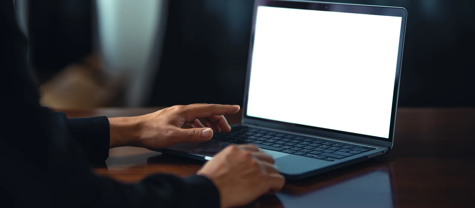 Hände an einem Laptop in einem dunklen Büro